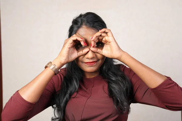 Asian Indian origin dark skin tone beautiful woman facial hand expression making faces hand signs funny looking through finger binocular