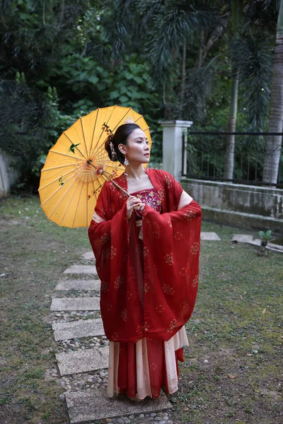 다색의 중국식붉은 치마를 매력적 아시아 우산으로 스카프를 바깥의 정원의 — 스톡 사진