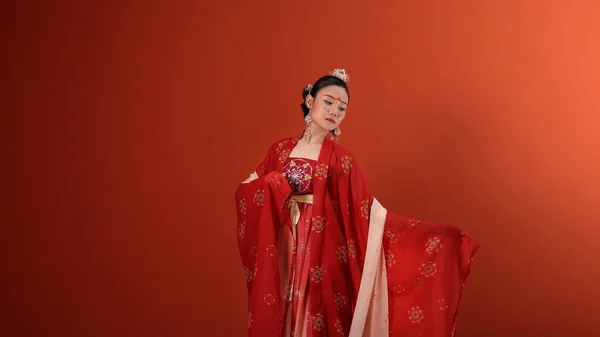 若い魅力的なアジアの女性を身に着けている伝統的な中国の赤い半布ロングスカートの衣装スカーフヘアピンピアス室内で読み取りマロンの背景壁 — ストック写真