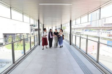 Dört çekici Asyalı kadın arkadaş arkadaş arkadaşlarımız konuşuyor. Yürüyüş öğrencileri konuşuyor. Sırt çantalarını dışarıda gezdiriyorlar.