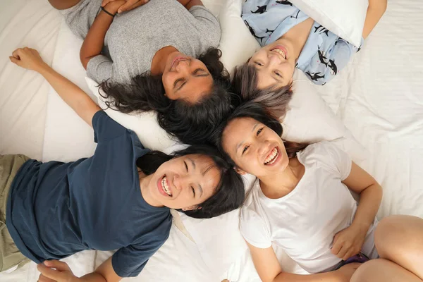 Young Asian girls sleepover pajama party happy joy funny laugh smile on large bed in bedroom with bright light window