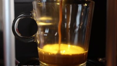 Taze sıvı kahve kümes hayvanları makineden şeffaf cam bardağa dökülüyor. 