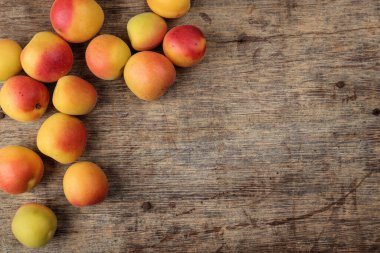 Fresh ripe juicy yellow orange red apricot fruit pile whole cut half slice seed on rustic wood background flat lay top view border frame copy text space 