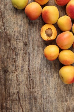 Fresh ripe juicy yellow orange red apricot fruit pile whole cut half slice seed on rustic wood background flat lay top view border frame copy text space 