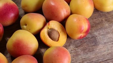 Fresh ripe juicy yellow orange red apricot fruit pile whole cut half slice seed on rustic wood background flat lay top view pan move shift 