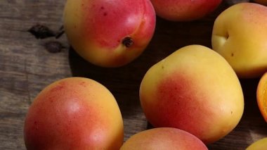 Fresh ripe juicy yellow orange red apricot fruit pile whole cut half slice seed on rustic wood background flat lay top view pan move shift 