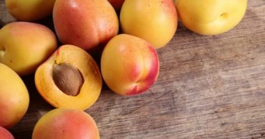 Fresh ripe juicy yellow orange red apricot fruit pile whole cut half slice seed on rustic wood background flat lay top view pan move shift 