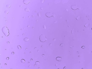 Mor arka planda yağmur damlaları. Bardak su damlalarıyla kaplı. Yumuşak odak