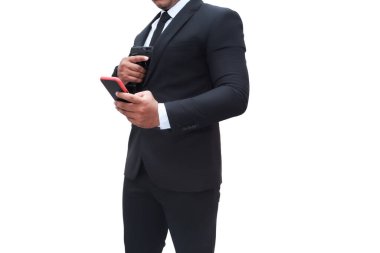 Siyah takım elbiseli silahlı bir adam tabanca tutuyor ve diğer eli de beyaz bir arka plan görevinde hedefini kontrol etmek için cep telefonuna gidiyor. Suikastçı, katil, suçlu, hırsız kavramı.