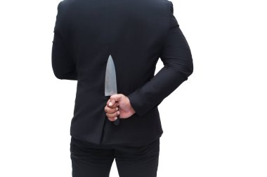 Siyah takım elbiseli bir iş adamı beyaz arka planda sırtında bıçak taşıyor.