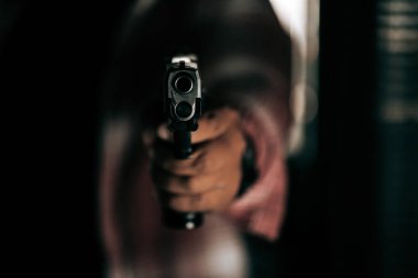 Çizgili tişörtlü, silahlı bir suçlu kapıyı kırıp içeri giriyor ve silahını ceza konseptine doğrultuyor..