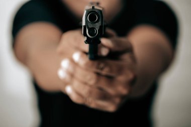 Siyah gömlekli suçlu bir tabanca tutuyor ve hedefe nişan alıyor, yakın plan, soyguncu konsepti..