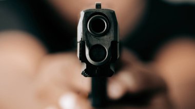 Siyah gömlekli suçlu bir tabanca tutuyor ve hedefe nişan alıyor, yakın plan, soyguncu konsepti..