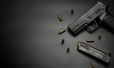 Tabanca siyah bir zemine yerleştirilmiş ve her tarafı 9 mm 'lik mermilerle çevrilmiş. Kurban silahı için fikir.