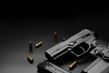 Siyah tabanca koyu bir arka plana yerleştirilir ve etrafına 9 mm 'lik cephane yerleştirilir. Ve dergileri olan bir polis telsizi. Dedektifler için fikir.