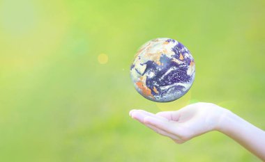 Yeşil doğa arka planında Dünya gezegeni küresi ellerde. Çevre koruma kavramı. Bu görüntünün elementleri NASA tarafından desteklenmektedir.