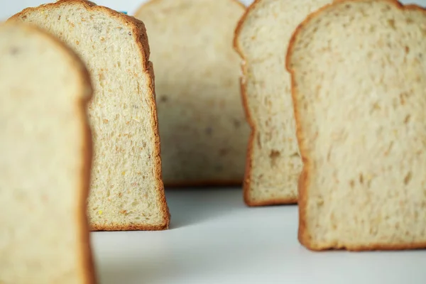 裏側の列に数枚のスライスしたパンが並べられ 中央にはパンのスライスに焦点が当てられた 白い背景の上に — ストック写真