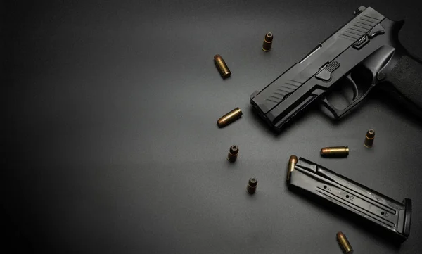 Tabanca siyah bir zemine yerleştirilmiş ve her tarafı 9 mm 'lik mermilerle çevrilmiş. Kurban silahı için fikir.