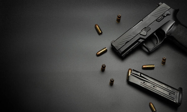 The handgun is placed on a black background with 9 mm bullets all around. Idea for victim gun.