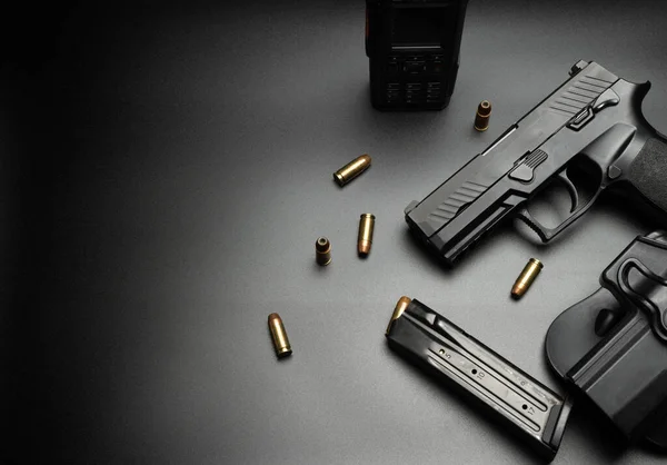 Siyah tabanca koyu bir arka plana yerleştirilir ve etrafına 9 mm 'lik cephane yerleştirilir. Ve dergileri olan bir polis telsizi. Dedektifler için fikir.