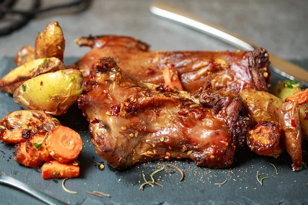 Homemade roast rat, Steak knife, fork, dipping sauce, steak knife, potato wedges close up on a slate board with dark gray color paint, old crumpled paper. Horizontal top view from above,grilled rats.