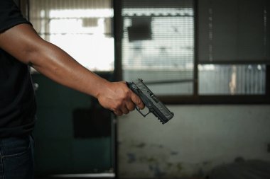 Elinde tabanca olan bir adam, siyah bir odada duruyor, bir hedefi hedef alıyor ve nişan alıyor. Suikast, cinayet, suç kavramı