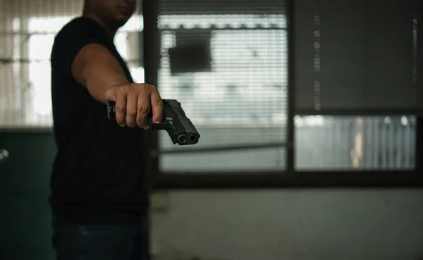 拳銃を持っている男は 黒の部屋に立って 標的に銃を向けている 暗殺殺人犯罪という概念を — ストック写真