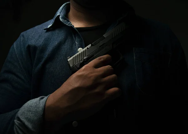 Man Blue Denim Shirt Standing Dark Room Holding Pistol His — Stock Photo, Image