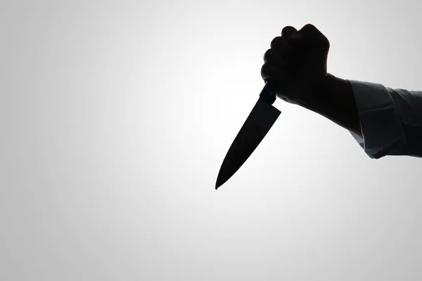Beyaz arka planda bıçak tutan suçlu el silueti, kesilmiş
