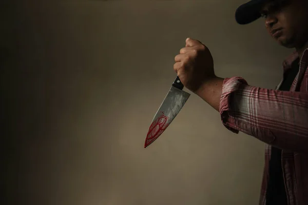 血のついたナイフを持つキャップの長い袖の犯罪者は テキスト 概念犯罪 殺人のためのスペースで オレンジ色黒の背景に残酷に犠牲者を攻撃しています — ストック写真