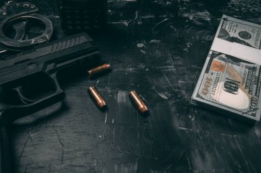 Siyah tabancalar, kelepçeler, kurşunlar, dolar banknotları ve polis telsizleri. Siyah ahşap bir masaya yerleştirilmiş. Yolsuzluk polisi kavramı. coppy alanı ile