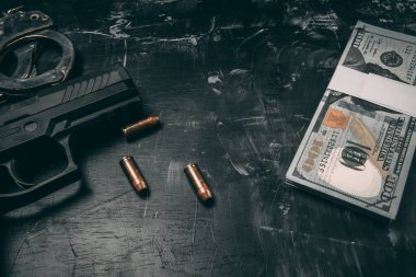 Siyah tabancalar, kelepçeler, kurşunlar, dolar banknotları ve polis telsizleri. Siyah ahşap bir masaya yerleştirilmiş. Yolsuzluk polisi kavramı. coppy alanı ile