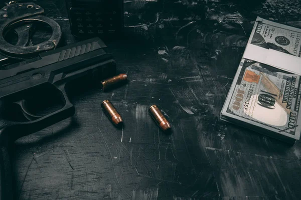 Siyah tabancalar, kelepçeler, kurşunlar, dolar banknotları ve polis telsizleri. Siyah ahşap bir masaya yerleştirilmiş. Yolsuzluk polisi kavramı. coppy alanı ile