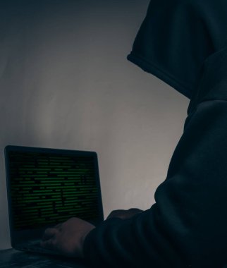 The hacker was wearing a black hoodie. Stealing huge financial data on computers with binary code digital interface.Hacking and malware concept.