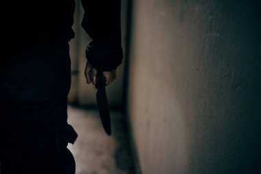 Korkunç, karanlık bir odada elinde bıçak olan bir katilin, kurbana saldırmak üzere olduğu görüntüsü..
