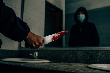 Katilin arkasında kurbanı öldüren kanlı bir bıçak vardı. Banyoda, aynada kendine korkunç ve korkunç bir şekilde bakıyordu..