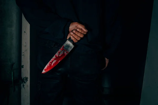 Behind the murderer the man held a bloody knife that killed the victim. horribly and terrifying