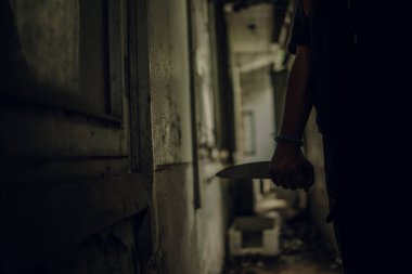 The shadow of a female murderer stood with a knife in a terrifying wasteland, illuminated from behind.Scary horror or thriller movie mood or nightmare at night Murder or homicide concept.