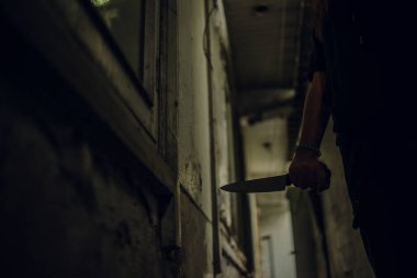The shadow of a female murderer stood with a knife in a terrifying wasteland, illuminated from behind.Scary horror or thriller movie mood or nightmare at night Murder or homicide concept.