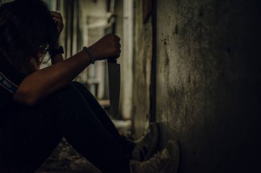 The shadow of a female murderer stood with a knife in a terrifying wasteland, illuminated from behind.Scary horror or thriller movie mood or nightmare at night Murder or homicide concept.