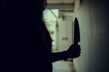 Kadın bir katilin gölgesi korkunç bir şekilde elinde bir bıçakla ve arkadan aydınlatılarak dikildi. Korku, gerilim filmi havası ya da gece kâbusu cinayet ya da cinayet kavramı..