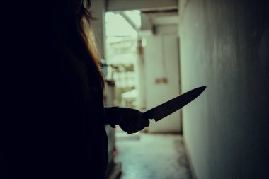 Kadın bir katilin gölgesi korkunç bir şekilde elinde bir bıçakla ve arkadan aydınlatılarak dikildi. Korku, gerilim filmi havası ya da gece kâbusu cinayet ya da cinayet kavramı..