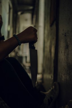 The shadow of a female murderer stood with a knife in a terrifying wasteland, illuminated from behind.Scary horror or thriller movie mood or nightmare at night Murder or homicide concept.
