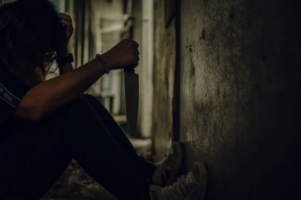 The shadow of a female murderer stood with a knife in a terrifying wasteland, illuminated from behind.Scary horror or thriller movie mood or nightmare at night Murder or homicide concept.