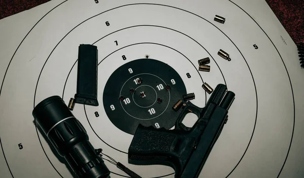 The pistol rests on a target with a bullet hole. close-up