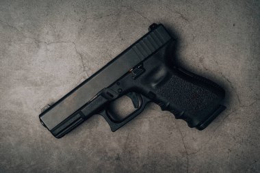 Eski beton zeminde 9 mm 'lik siyah bir tabanca. en üstteki görünüm.