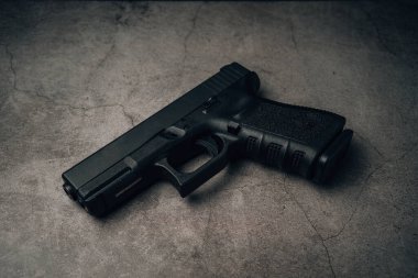 black 9mm pistol on an old concrete floor. top view.