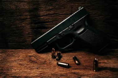 Eski ahşap bir zeminde 9 mm 'lik mermili siyah bir tabancanın portresi.