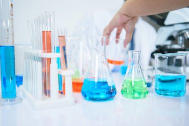 Asyalı bilim adamları laboratuvarda kimyasal bileşenleri ciddi şekilde inceliyorlar. Genç Biyoteknoloji Uzmanlığı Gelişmiş mikroskop ekipmanları kullanın.