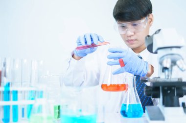 Asyalı bilim adamları laboratuvarda kimyasal bileşenleri ciddi şekilde inceliyorlar. Genç Biyoteknoloji Uzmanlığı Gelişmiş mikroskop ekipmanları kullanın.